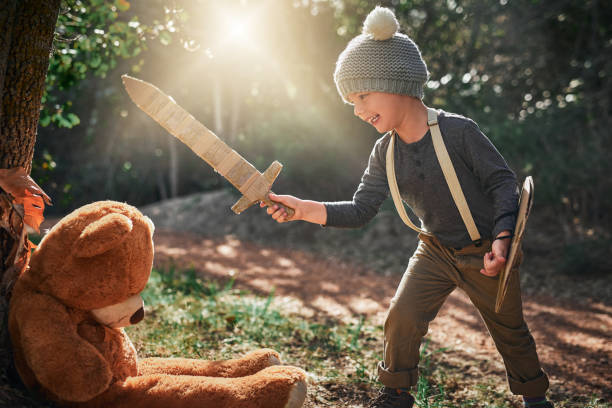 Shot of an adorable little boy playing with a cardboard sword and shield outside