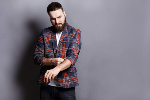 Bearded man in shirt adjusting sleeves copy space Bearded man in checkered jacket preparing to work hard, adjusting sleeves, copy space, gray studio background rolled up sleeves stock pictures, royalty-free photos & images