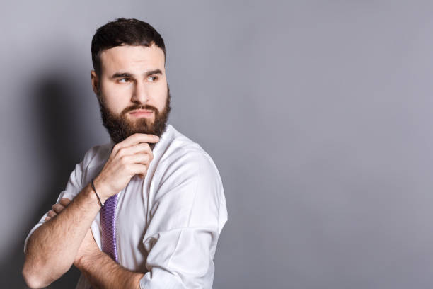 istock Pensive bearded businessman with hand on chin 812997550