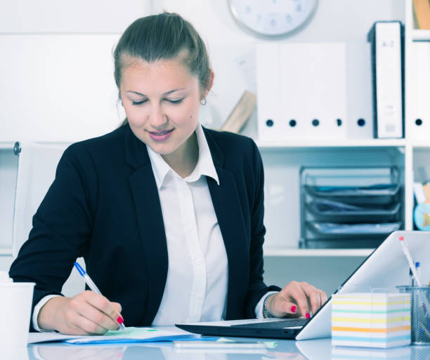 istock Woman employee is working with documents and laptop 812998784