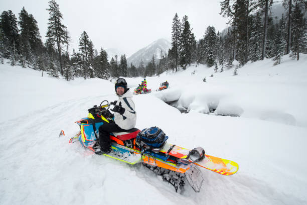 istock Reaching the snowboarding spots by snowmobile in mountain forest. 813001882