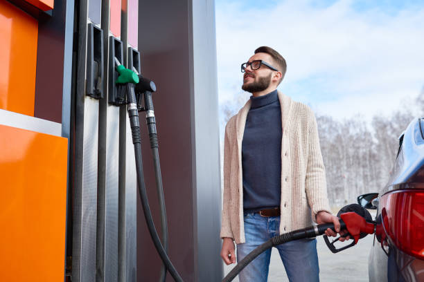 улыбающийся человек, глядя на топливный счетчик на азс - gasoline filling gas station car стоковые фото и изображения