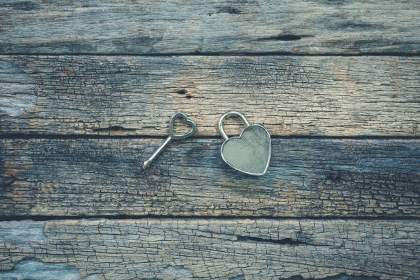 istock Shiny heart lock and key on rustic wood table background 813008588