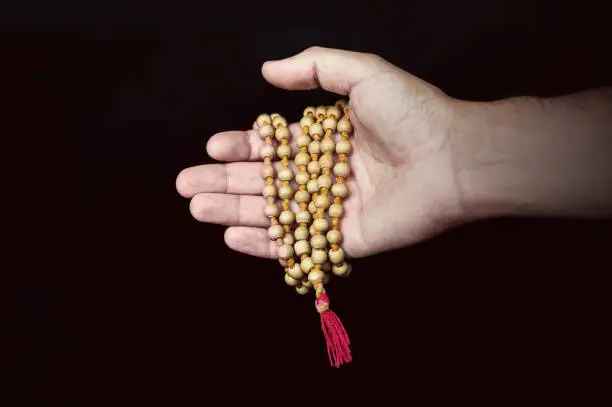wooden Islamic prayer beads in hand on black background