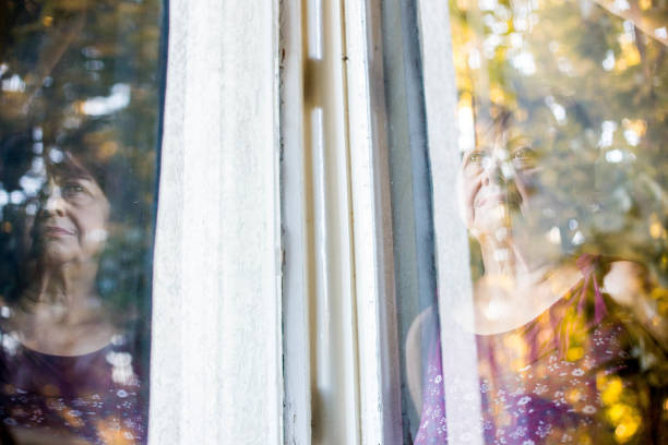 istock Senior woman looking throught the window 813011672