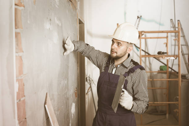 istock Male builder is checking the quality of the work done after the plaster wall 813016260