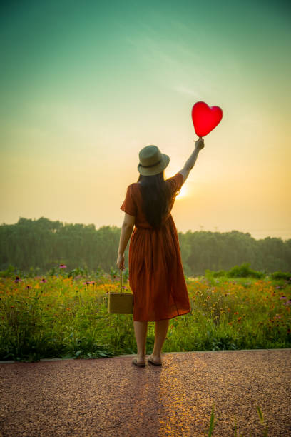istock Young woman holding heart-shaped balloon 813016340
