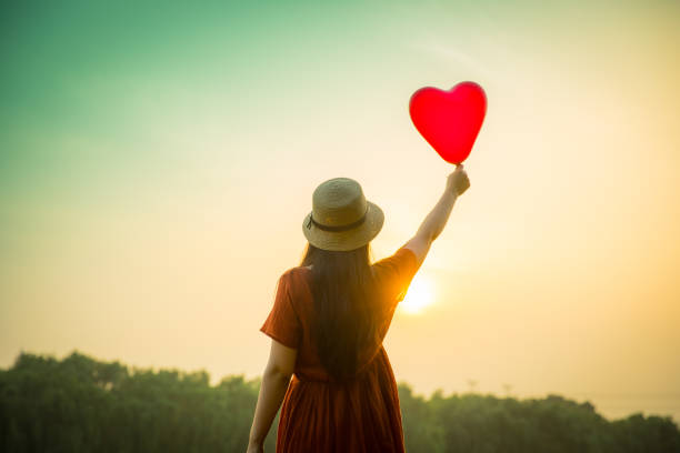 istock Young woman holding heart-shaped balloon 813016416