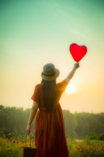 istock Young woman holding heart-shaped balloon 813016424