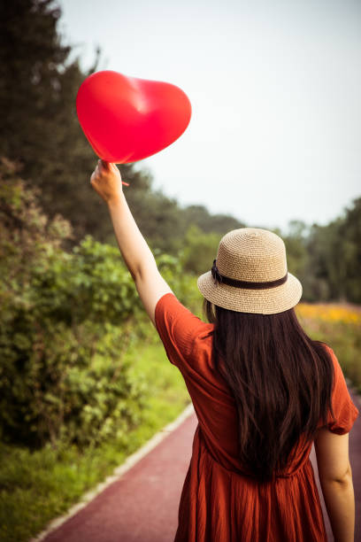 istock Young woman holding heart-shaped balloon 813016478