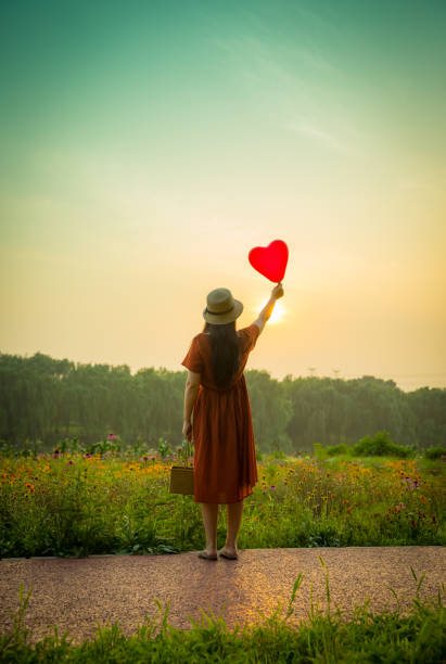 istock Young woman holding heart-shaped balloon 813019136