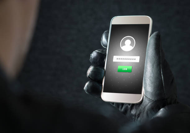 Identity theft and cyber security concept. Mobile hacker and criminal login to persons online social media account or personal information and data with smartphone. Thief with black leather gloves.