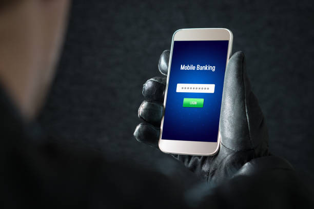 istock Mobile banking hack and cyber security concept. Hacker and criminal login to persons online bank application and steal money from account with smartphone. Thief with black leather gloves. 813024650