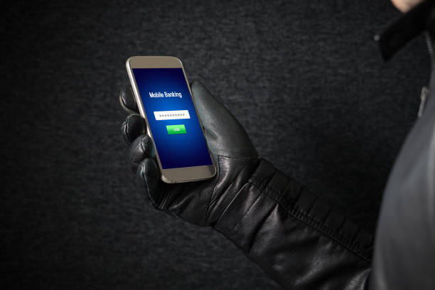 istock Mobile banking hack and cyber security concept. Hacker and criminal login to persons online bank application and steal money from account with smartphone. Thief with black leather gloves. 813024756