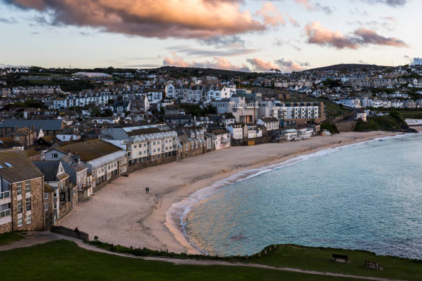 Beach Saint Ives Saint Ives, England - April 28, 2017: Sunset at the beach of Saint Ives with the ocean and the Cornish landscape. st ives cornwall stock pictures, royalty-free photos & images