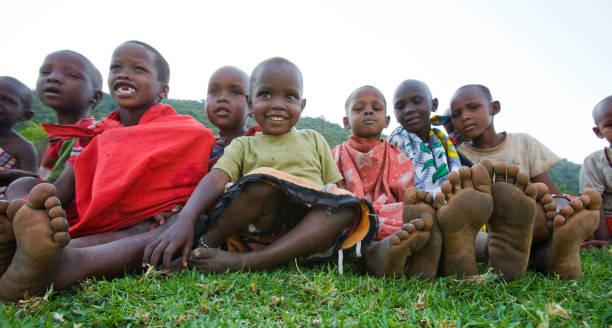 Maasai children sit together on the ground. stock photo
