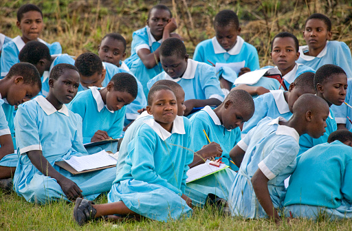 School students sit on the earth and wait for the school bus. Kenya, Masai Mara, July 18, 2008.