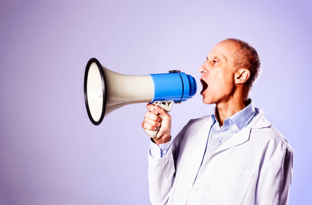 istock Goofy mature man in lab coat calling into bullhorn 813041408
