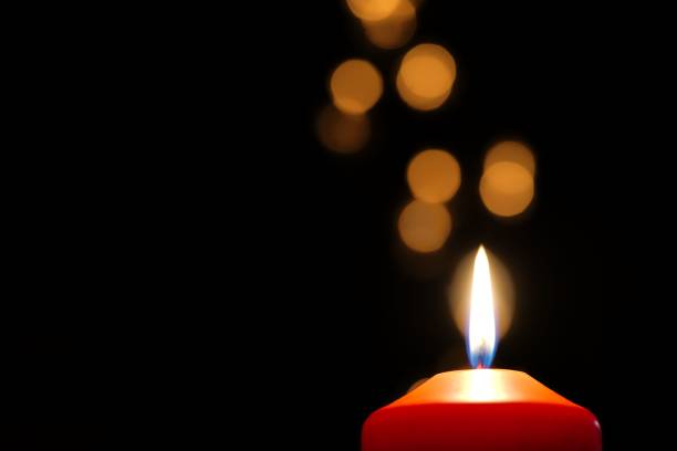 istock Single red candle burning in darkness with golden bokeh 813053028