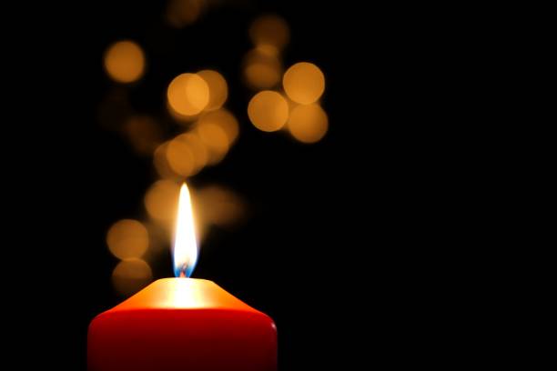istock Red burning candle with golden bokeh against black background 813053078