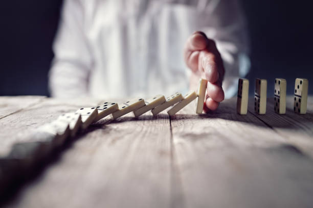 Stop the domino effect concept for business solution and intervention Stopping the domino effect concept for business solution, strategy and successful intervention man hand down stock pictures, royalty-free photos & images