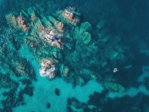 Aerial view of blue sea, rocks and a small boat