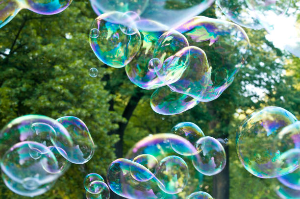 istock Soap bubbles in front of green trees 813068464