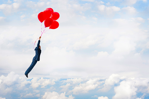 business freedom concept businessman flying above the clouds with balloons