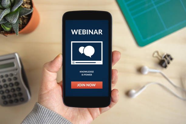 Hand holding smart phone with webinar concept on screen stock photo