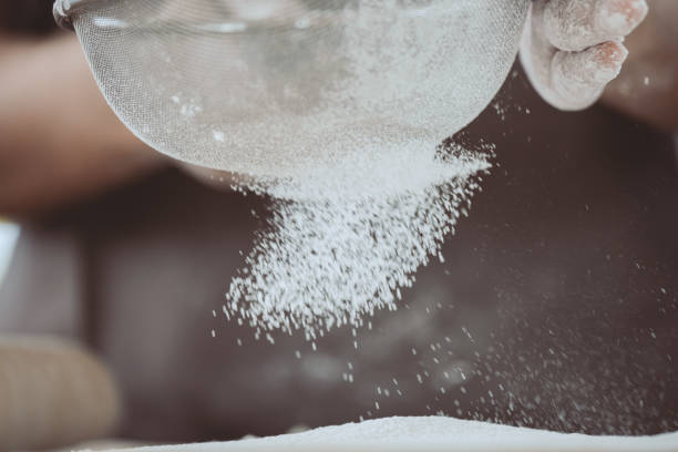 istock Woman prepare bread dough, spreading the flour through a sieve on dough 813074100