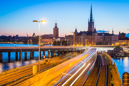 Commuter train zooming towards the underground station below the iconic spire of Tyska kyrkan in the historic Gamla Stan district of downtown Stockholm, Sweden.