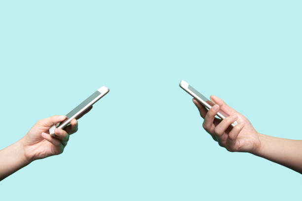 dos manos sosteniendo los teléfonos móviles - isolated on red fotografías e imágenes de stock