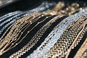 silver and gold necklaces and bracelets lying on black background