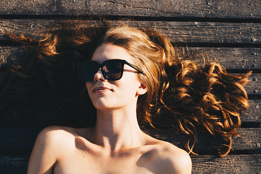 Beautiful red head girl with sunglasses laying on a patio