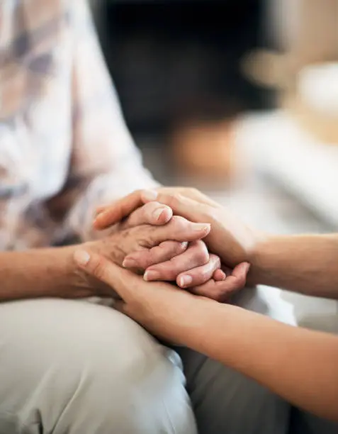 Cropped shot of an unidentifiable nurse consoling her elderly patient by holding her hands at home