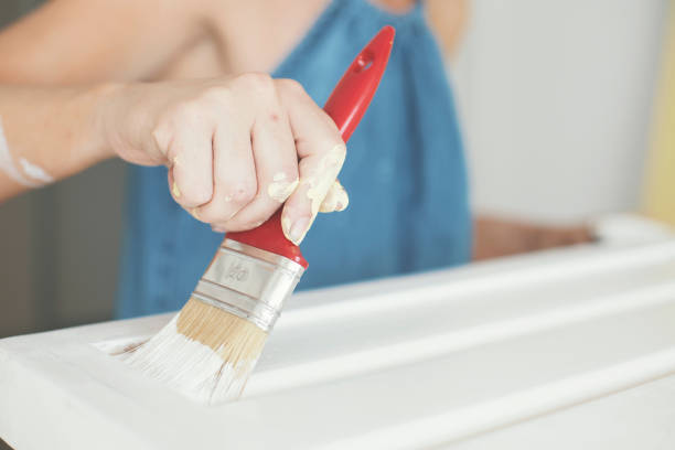 Hand of a woman holding paint brush.