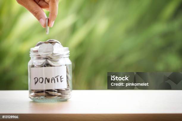 Hand Putting Coins In Glass Jar For Giving And Donation Concept Stock Photo - Download Image Now