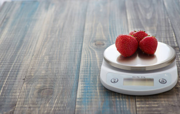 Strawberry on the scales Three ripe strawberry berries lie on electronic kitchen scales vintage kitchen scale with fruit stock pictures, royalty-free photos & images