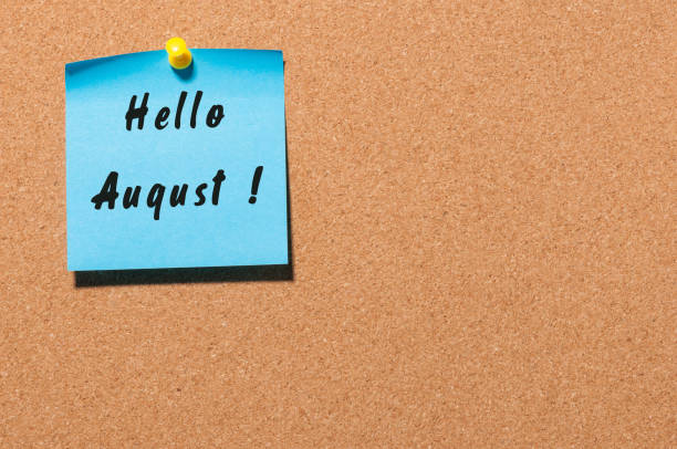 istock Hello August on blue sticker pinned to cork noticeboard with empty space for text 813155572