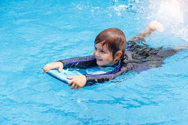 istock little boy learning to swim in pool, practicing with foam pad 813160828