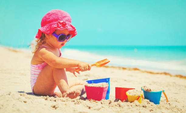 istock cute little girl play with sand on beach 813166926