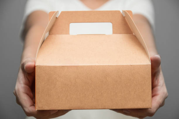 a woman in white t-shirt stood bringing a snack box - box lunch fotos imagens e fotografias de stock