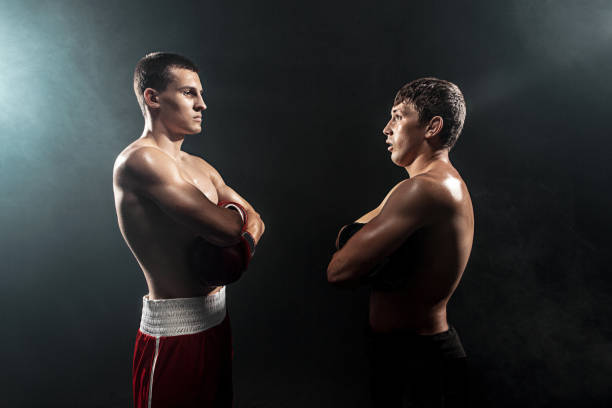 Two professional boxer standing on black smoky studio background.
