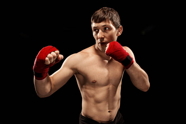 istock Male boxer boxing in punching bag with dramatic edgy lighting in a dark studio 813195302