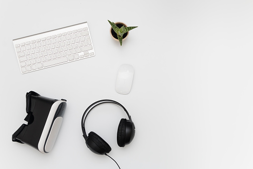 Escritorio con dispositivo de realidad virtual, Headphones, teclado, ratón y una planta grasa photo