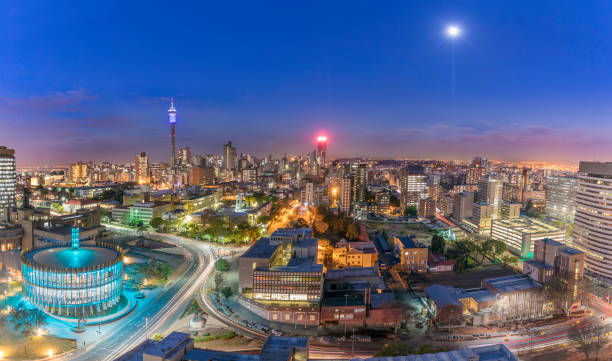 Johannesburg Council Chamber and Hillbrow cityscape Johannesburg cityscape and moonlight, taken at sunset, showing the illuminated Council Chamber which is set to be the centre for the revitalisation and urban renewal of the precinct. Hillbrow residential area and the prominent communications tower and Ponte flats. johannesburg photos stock pictures, royalty-free photos & images