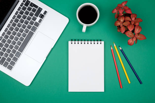 istock Modern green office desk table with laptop and blank notebook page for input the text. Top view, flat lay 813204928