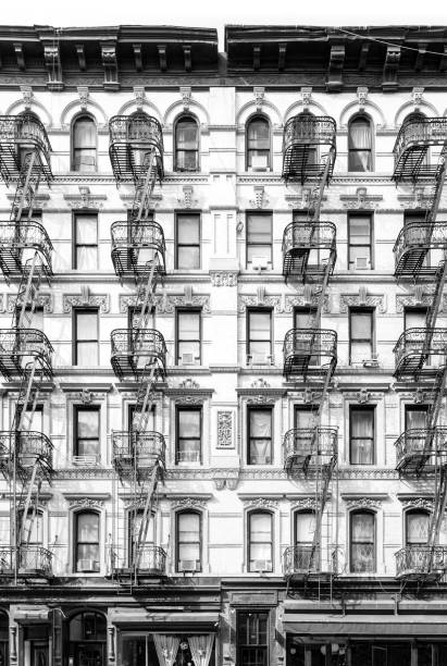 New York City vintage apartment building in black and white New York City vintage apartment building with windows and fire escapes in black and white east photos stock pictures, royalty-free photos & images