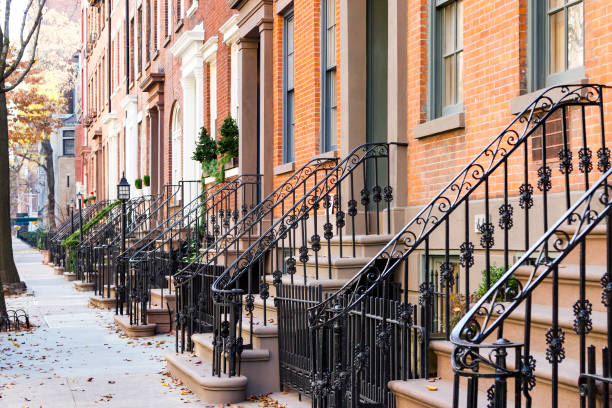 row of old historic brownstone buildings along an empty sidewalk block in the greenwich village neighborhood of manhattan, new york city nyc - front stoop imagens e fotografias de stock