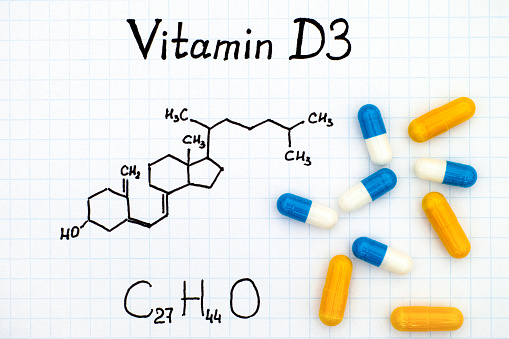 Chemical formula of Vitamin D3 and some pills.